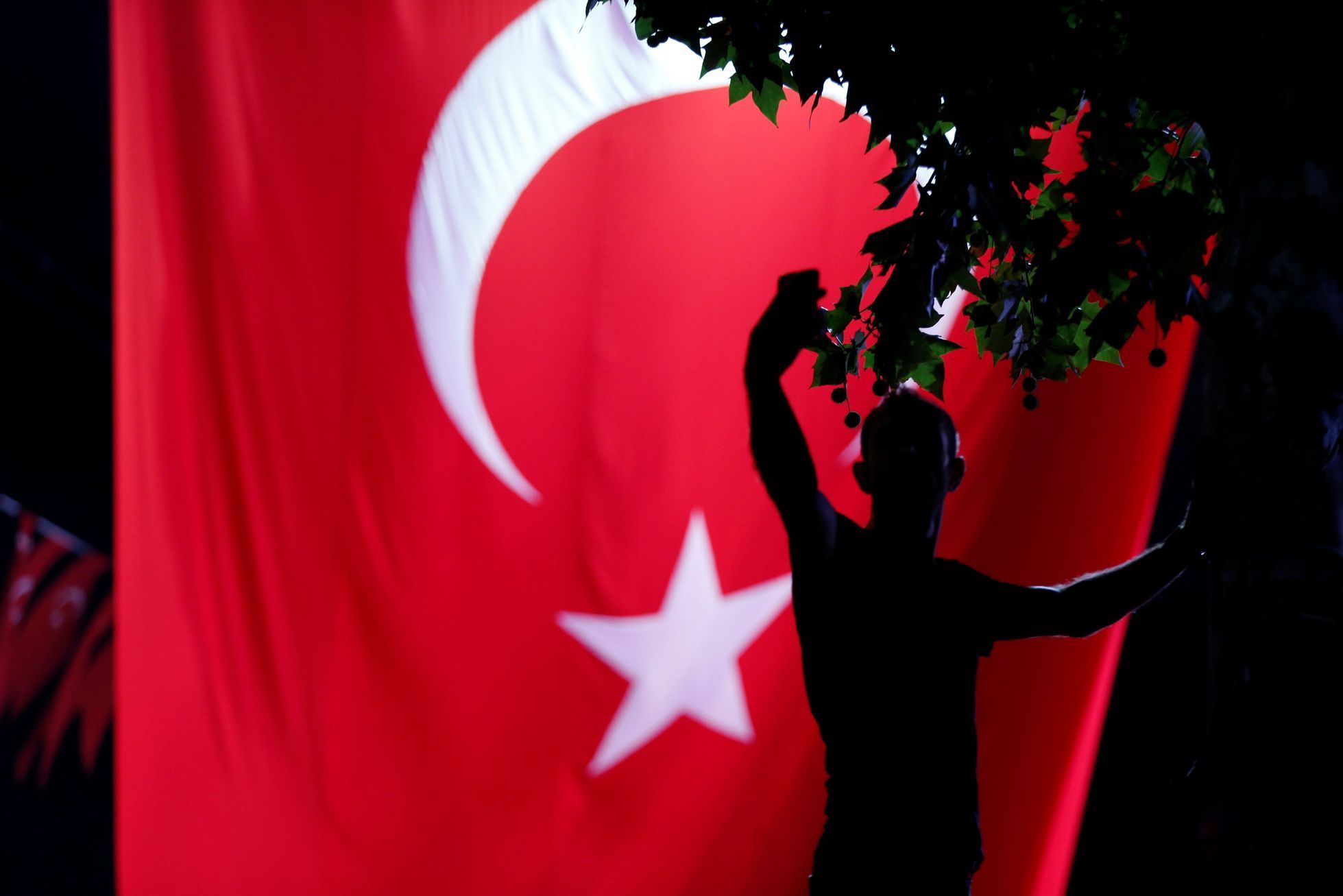 Příznivec tureckého prezidenta Erdogana se fotí před obrovskou tureckou vlajkou na Taksimském náměstí v Istanbulu
