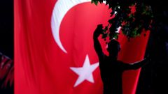 Příznivec tureckého prezidenta Erdogana se fotí před obrovskou tureckou vlajkou na Taksimském náměstí v Istanbulu
