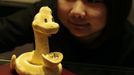 A staff member poses with a 24K gold sculpture in the shape of a snake carrying an ingot, designed for the year of the snake, at a jewellery store in Hong Kong January 29, 2013. The item weighs 5.219 Chinese taels (195 grams) and sells for HK$104,000 ($12,872). The Lunar New Year, also known as the Spring Festival, begins on February 10 and marks the start of the Year of the Snake, according to the Chinese zodiac. Picture taken January 29, 2013. REUTERS/Bobby Yip (CHINA - Tags: SOCIETY BUSINESS) Published: Úno. 8, 2013, 6:10 dop.