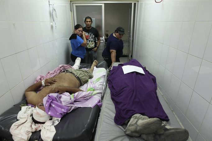 People observe the dead body of a family member who had died of gunshot wounds after being attacked by a gang while a patient lying on a stretcher covers his face at the emergency ward of a local hospital in San Pedro Sula March 20, 2013. San Pedro Sula, the country's second largest city after Tegucigalpa, has a homicide rate of 169 per 100,000 people and was named the world's most violent city for a second year in a row. Lax laws allow civilians to own up to five personal guns. Arms trafficking has flooded the country with nearly 70% illegal firearms. 83.4% of homicides are by firearms, compared to 60% in the United States. Picture taken March 20, 2013. REUTERS/Jorge Cabrera (HONDURAS - Tags: CRIME LAW CIVIL UNREST HEALTH) ATTENTION EDITORS: PICTURE 19 OF 39 FOR PACKAGE 'GUN CULTURE - HONDURAS' SEARCH 'HONDURAS GUN' FOR ALL IMAGES Published: Dub. 5, 2013, 11:14 dop.