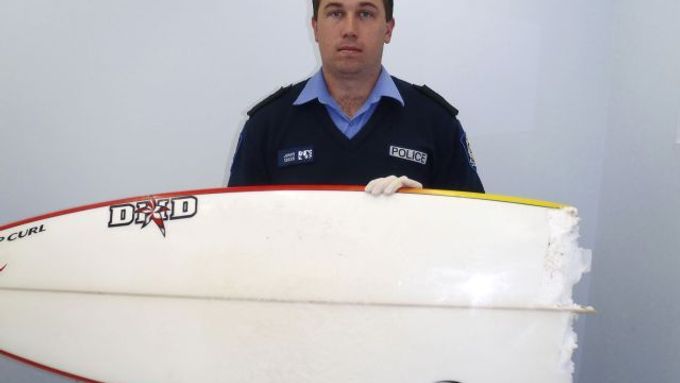 Australský policista ukazuje novinářům překousnuté surfařské prkno. Jeho majitel útok žraloka u západoaustralského pobřeží 17. srpna tohoto roku nepřežil.