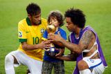 Brazilec Marcelo (vpravo) pomáhá sému synkovi držet vítěznou trofej, asistuje jim také Neymar.