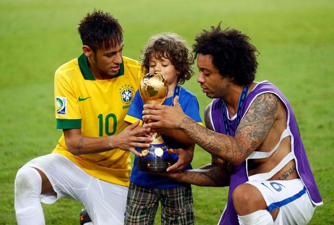 Brazil's Marcelo (R) helps his son hold the trophy as teammate Neymar looks on as they celebrate winning their Confederations Cup final soccer match against Spain at the