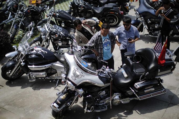 Local residents look at a Harley Davidson motorcycle during the annual Harley Davidson National Rally in Qian Dao Lake, in Zhejiang Province May 11, 2013. Around 1,000 Harley Davidson enthusiasts from all over China met to celebrate the 5th Harley Davidson National Rally in China, as part of the company's 110-year anniversary. Major Chinese cities ban motorcycles from circulating on highways and major avenues. Meanwhile, Harley Davidson motorbikes are considered by Chinese tax authorities to be luxury items, so they are taxed at extremely high rates-- sometimes the taxes alone is equivalent to the bike's U.S. price tag. Traffic and transportation authorities have also weighed in, putting Harleys in the same category as electric bikes, horses and bicycles, meaning that they cannot be on highways and major avenues. Picture taken May 11, 2013. REUTERS/Carlos Barria (CHINA - Tags: TRANSPORT SOCIETY) Published: Kvě. 13, 2013, 11:05 odp.