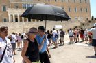Jeden z návštěvníků se chrání před spalujícími paprsky deštníkem přímo před řeckým parlamentem ve skleníkovém horku athénského léta.