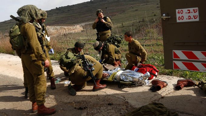 Izraelští vojáci evakuují zraněného kolegu na Golanských výšinách. (18. března 2014)