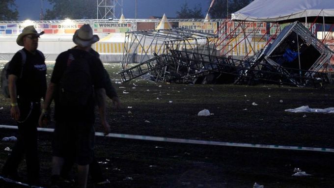 Dobrovolníci přihlížejí na trosky stanu, který strhla bouře během velkého hudebního festivalu v Belgii