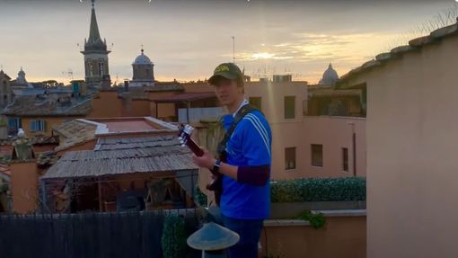 Mladík povzbuzuje Italy v době karantény hrou na kytaru nad Piazza Navona.