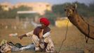 A camel herder smokes on while waiting for customers at Pushkar Fair in the desert Indian state of Rajasthan November 22, 2012. Many international and domestic tourists throng to Pushkar to witness one of the most colourful and popular fairs in India. Thousands of animals, mainly camels, are brought to the fair to be sold and traded. REUTERS/Danish Siddiqui (INDIA - Tags: ANIMALS SOCIETY) Published: Lis. 22, 2012, 4:10 odp.