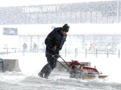 Pracovníci úklidových čet odklízejí sníh před terminálem pražského mezinárodního letište v Ruzyni, které bylo 12. března kvůli silnému sněžení mimo provoz.