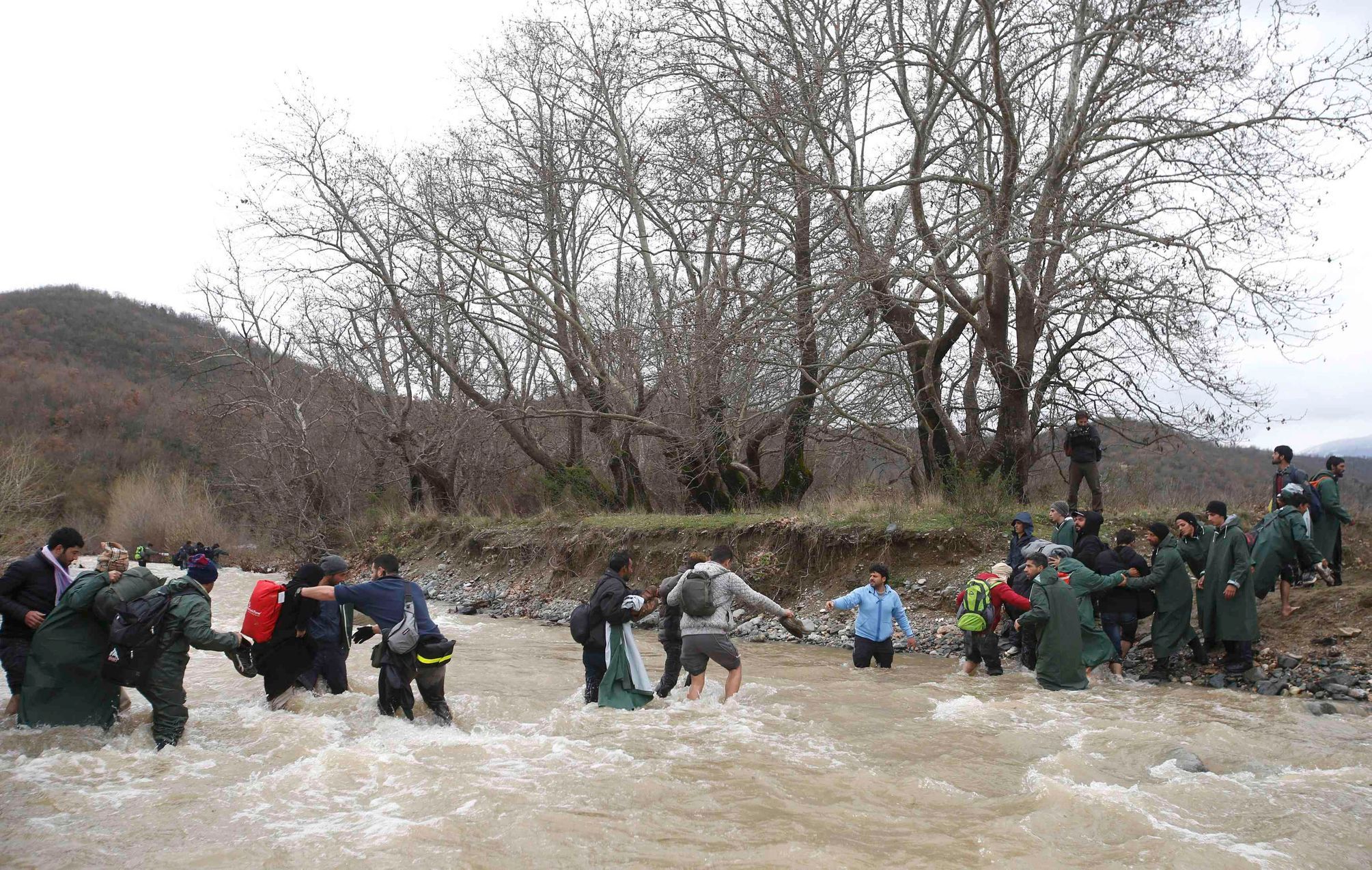 Běženci přecházejí řeku západně od Idomeni.