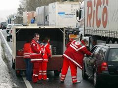 Členové Červeného kříže roznášejí - mezi řidiči mrznoucími v dopravní zácpě - kávu a čaj.