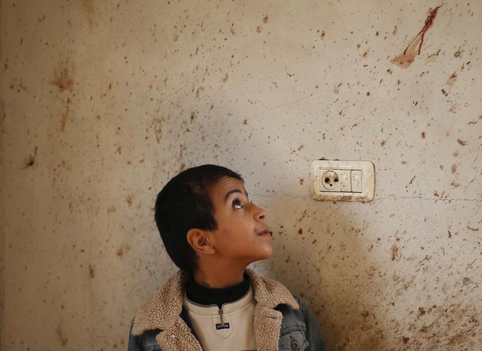 The brother of Palestinian boy Faris Basyoni, who was killed in an Israeli air strike, looks at his blood on a wall at his family's damaged house in Beit Hanoun in the northern Gaza Strip November 16, 2012. Basyoni was killed on Thursday night when an Israeli air strike hit his family house. Egypt opened a tiny window to emergency peace diplomacy in Gaza on Friday, but hopes for even a brief ceasefire while its prime minister was inside the bombarded enclave to talk to leaders of the Islamist Hamas movement were immediately dashed. REUTERS/Suhaib Salem (GAZA - Tags: CIVIL UNREST MILITARY POLITICS) Published: Lis. 16, 2012, 11 dop.