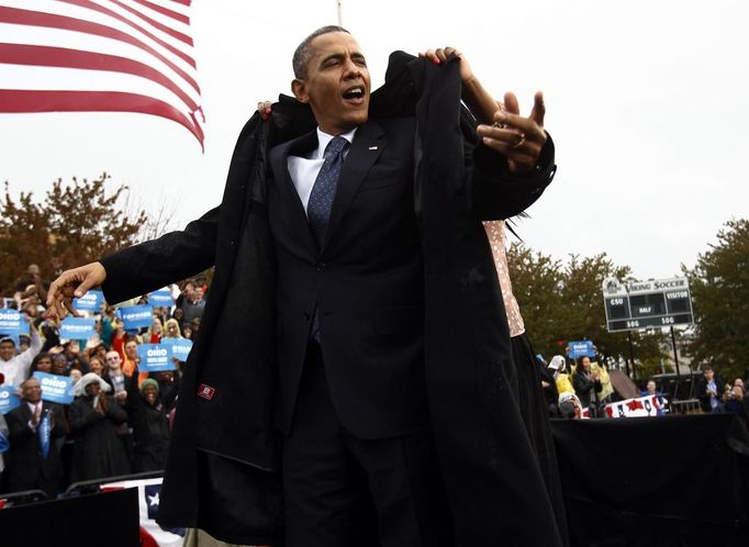 U.S. President Barack Obama gets some help putting on his rain coat during a campaign rally in Cleveland, Ohio October 5, 2012. REUTERS/Kevin Lamarque (UNITED STATES - Tags: POLITICS ELECTIONS USA PRESIDENTIAL ELECTION) Published: Říj. 5, 2012, 7:14 odp.