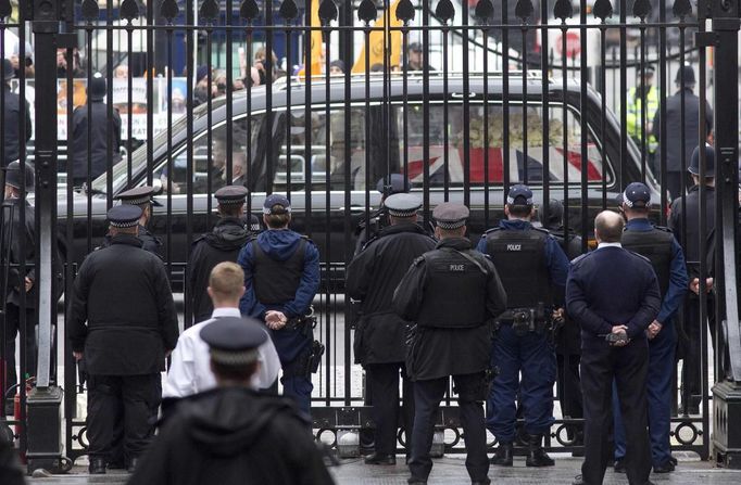 Smuteční vůz s rakví projíždí ulicí Downing street.