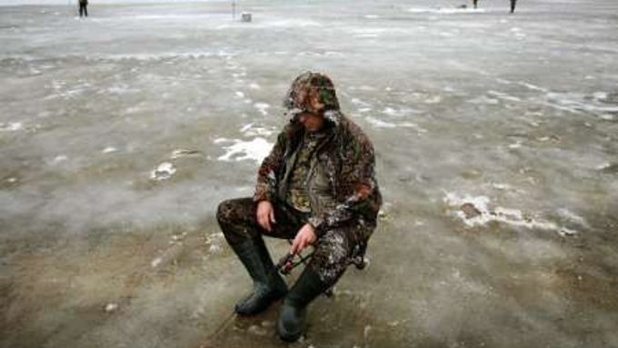 Rybář na zamrzlé řece Pripjať.