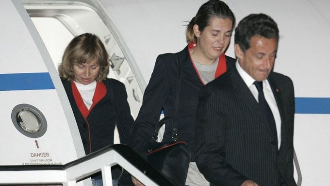 France's President Nicolas Sarkozy (R) leads two Spanish flight attendants off his plane after arriving to the Torrejon airbase outside Madrid November 4, 2007. The four female members of a Spanish air crew released by Chad arrived home on Sunday after flying out of the African country with Sarkozy. REUTERS/Susana Vera (SPAIN)