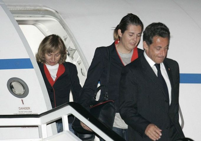 France's President Nicolas Sarkozy (R) leads two Spanish flight attendants off his plane after arriving to the Torrejon airbase outside Madrid November 4, 2007. The four female members of a Spanish air crew released by Chad arrived home on Sunday after flying out of the African country with Sarkozy. REUTERS/Susana Vera (SPAIN)