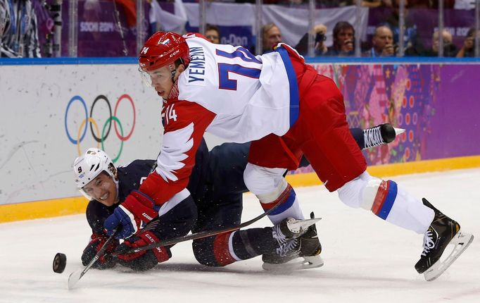 Team USA's Zach Parise (L) and Russia's Alexei Yemelin battle for the puck during the first period of their men's preliminary round ice hockey game at the Sochi 2014 Wint