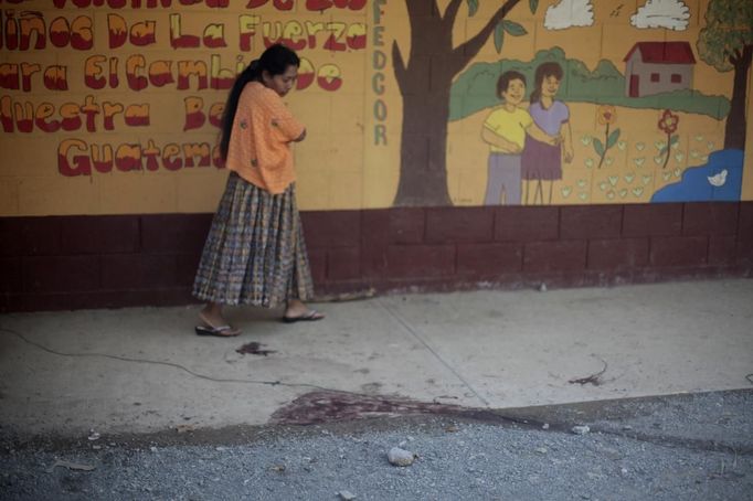 A woman walks past the blood stain of a man who was lynched and burnt alive by a mob after killing two children in a classroom at a primary school in Tactic, in Alta Verapaz region, some 189km (117 miles) from Guatemala City, September 12, 2012. According to local media, a man entered a school and killed two children, a 8-year-old and a 13-year-old, with a machete. REUTERS/Jorge Dan Lopez (GUATEMALA - Tags: EDUCATION CRIME LAW) Published: Zář. 13, 2012, 1:30 dop.