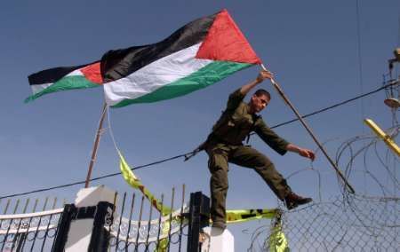 Palestinci vyvěšují vlajku u právě otevřeného přechodu v Rafáhu