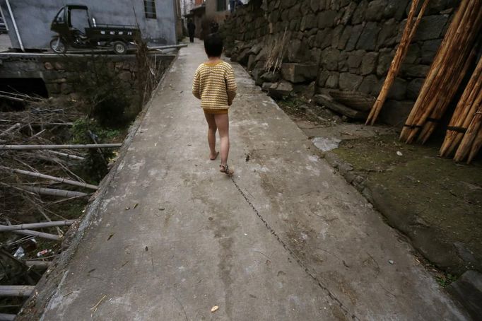 Eleven-year-old He Zili runs along an alley outside his home, as his father pulls on the chain locked around his ankle, in Zhejiang province