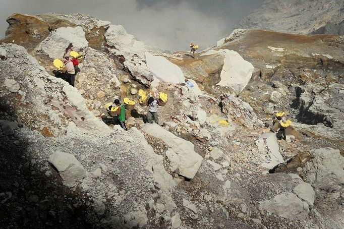 his photo taken on December 25, 2010 shows Indonesian miners carrying baskets of sulphur from the bottom of the crater of Indonesia's active Kajah Iwen volcano, in the extreme east of Java island. Some 350 sulphur miners eke out a dangerous and exhausting living on the active volcano, carrying hauls of up to 80 kilos of "yellow gold" which will be bought by local factories and used to refine sugar or make matches and medicines. The miners extract the liquid sulphur as it flows out of hot iron pipes. Once in the open air, it cools, crystallises and turns bright yellow. The sulphur is then loaded into wicker baskets at either end of bamboo yokes and carried back over the lip of the crater and down the side of the volcano, a treacherous journey of four kilometres (2.5 miles).