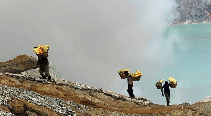 This photo taken on December 25, 2010 shows Indonesian miners carrying baskets of sulphur from the bottom of the crater of Indonesia's active Kajah Iwen volcano, in the extreme east of Java island. Some 350 sulphur miners eke out a dangerous and exhausting living on the active volcano, carrying hauls of up to 80 kilos of "yellow gold" which will be bought by local factories and used to refine sugar or make matches and medicines. The miners extract the liquid sulphur as it flows out of hot iron pipes. Once in the open air, it cools, crystallises and turns bright yellow. The sulphur is then loaded into wicker baskets at either end of bamboo yokes and carried back over the lip of the crater and down the side of the volcano, a treacherous journey of four kilometres (2.5 miles).