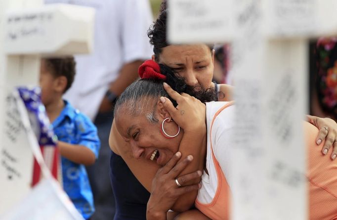 Denise Paba, who lost her 6-year-old niece Veronica Moser, is comforted by a woman as she cries at a memorial for victims behind the theatre where a gunman opened fire last Friday on moviegoers in Aurora, Colorado July 22, 2012. Residents of a Denver suburb mourned their dead on Sunday from a shooting rampage by a "demonic" gunman who killed 12 people and wounded 58 after opening fire at a cinema showing the new Batman movie. President Barack Obama headed to Aurora, on Sunday to meet families grieving their losses Friday's mass shooting that has stunned the nation and rekindled debate about guns and violence in America. REUTERS/Shannon Stapleton (UNITED STATES - Tags: DISASTER SOCIETY CIVIL UNREST) Published: Čec. 23, 2012, 12:08 dop.