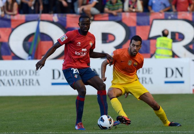 Fotbalista Barcelony Sergio Busquets napadá Rolanda Lamaha v utkání La Ligy 2012/13 s Osasunou.