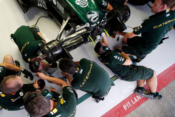 Mechanici stáje Caterham připravují zelený monopost před prvním pátečním tréninkem.