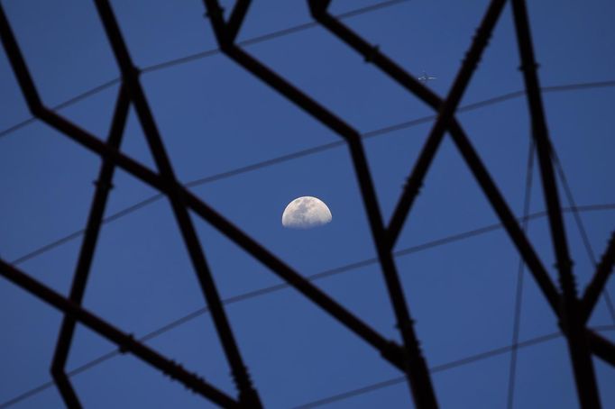 The moon is pictured through the structure of a giant concrete supertree at the Supertrees Grove at the Gardens by the Bay in Singapore June 28, 2012. The 101-hectare gardens situated at the heart of Singapore's new downtown at Marina Bay, which have two greenhouses and 220,000 plants from almost every continent, was officially opened by Singapore's Prime Minister Lee Hsien Loong on Thursday. REUTERS/Tim Chong (SINGAPORE - Tags: ENVIRONMENT SOCIETY TRAVEL) Published: Čer. 28, 2012, 4:11 odp.