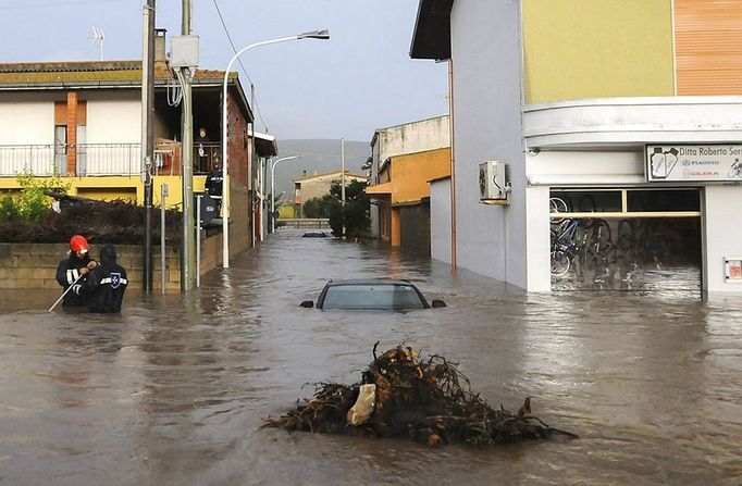 Záchranáři v ulicích městečka Uras, které po prudké bouři zaplavila voda.