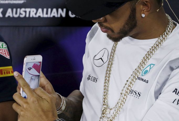 Mercedes F1 driver Lewis Hamilton takes a mobile phone picture of Ferrari F1 driver Sebastian Vettel during a news conference at the Australian Formula One Grand Prix in