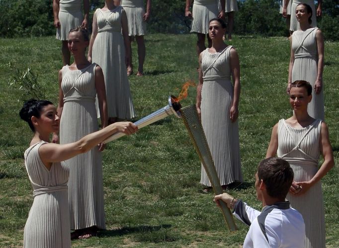 Greek actress Ino Menegaki (L), playing the role of High Priestess, lights the torch held by Spyridon Gianniotis, Greece's world champion of swimming, during a dress rehearsal for the torch lighting ceremony of the London 2012 Olympic Games at the site of ancient Olympia in Greece May 9, 2012. The official lighting ceremony for the London Games will take place on May 10. REUTERS/John Kolesidis (GREECE - Tags: SPORT OLYMPICS) Published: Kvě. 9, 2012, 11:25 dop.