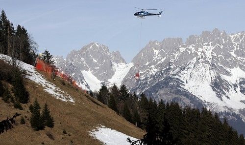 Vrtulník přepravuje sníh v Kitzbuehelu na sjezdovku