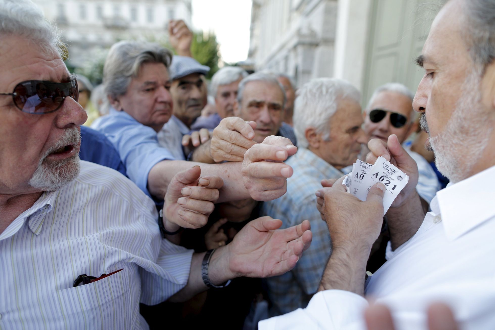 Řecko Pensioners are given priority tickets as they wait to receive part of their pensions at a National Bank branch in Athens