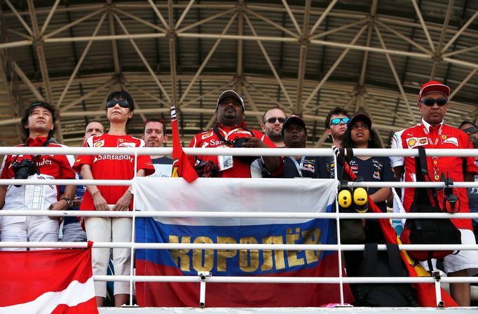 Fans stand during a one minute silence to show respect for the missing Malaysia Airlines flight MH370 before the start of the Malaysian F1 Grand Prix at Sepang Internatio