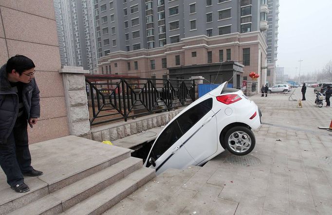 Road Cave-in In Weifang WEIFANG, CHINA - FEBRUARY 28: (CHINA OUT) A car is trapped in a huge hole after a cave-in happened at a gate of a residential community on February 28, 2013 in Weifang, Shandong Province of China. The cave-in occurred on Wednesday afternoon, engulfing a parked car. No casualties were reported.