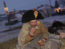 ROUSÍNOV (ČR) 2. prosince - Voják v uniformě napoleonského vojáka snídá chleba, když se v několikastupňovém mrazu probudil u vyhasínajícího ohně v polním ležení na návsi.