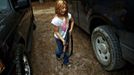 Brianna, 9, of the North Florida Survival Group carries an AK-47 rifle from the group leader's truck before heading out to conduct enemy contact drills during a field training exercise in Old Town, Florida, December 8, 2012. The group trains children and adults alike to handle weapons and survive in the wild. The group passionately supports the right of U.S. citizens to bear arms and its website states that it aims to teach "patriots to survive in order to protect and defend our Constitution against all enemy threats". Picture taken December 8, 2013. REUTERS/Brian Blanco (UNITED STATES - Tags: SOCIETY POLITICS) ATTENTION EDITORS: PICTURE 1 OF 20 FOR PACKAGE 'TRAINING CHILD SURVIVALISTS' SEARCH 'FLORIDA SURVIVAL' FOR ALL IMAGES Published: Úno. 22, 2013, 1 odp.