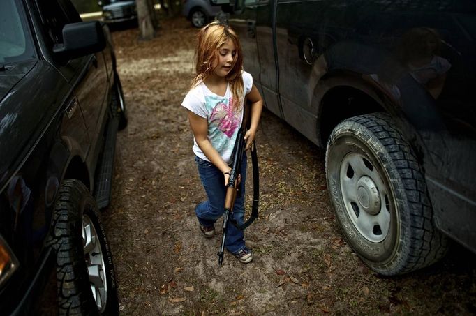 Brianna, 9, of the North Florida Survival Group carries an AK-47 rifle from the group leader's truck before heading out to conduct enemy contact drills during a field training exercise in Old Town, Florida, December 8, 2012. The group trains children and adults alike to handle weapons and survive in the wild. The group passionately supports the right of U.S. citizens to bear arms and its website states that it aims to teach "patriots to survive in order to protect and defend our Constitution against all enemy threats". Picture taken December 8, 2013. REUTERS/Brian Blanco (UNITED STATES - Tags: SOCIETY POLITICS) ATTENTION EDITORS: PICTURE 1 OF 20 FOR PACKAGE 'TRAINING CHILD SURVIVALISTS' SEARCH 'FLORIDA SURVIVAL' FOR ALL IMAGES Published: Úno. 22, 2013, 1 odp.