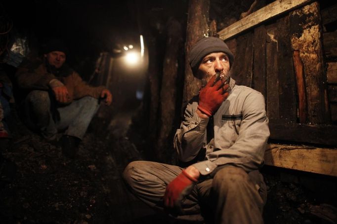 An illegal miner smokes a cigarrette during a break from digging at coal mine in the village of Stranjani, near Zenica, December 11, 2012. There are about 20 illegal mines in the area, where Bosnians dig for coal with their bare hands and use makeshift tools, such as bathtubs, to transport the coal. One bag of their coal is sold for 3 euros ($4 dollars), which is popular with the locals as it is cheaper than the coal sold at the city mine. REUTERS/Dado Ruvic (BOSNIA AND HERZEGOVINA - Tags: BUSINESS ENERGY SOCIETY CRIME LAW TPX IMAGES OF THE DAY) BOSNIA AND HERZEGOVINA OUT. NO COMMERCIAL OR EDITORIAL SALES IN BOSNIA AND HERZEGOVINA Published: Pro. 11, 2012, 4:46 odp.