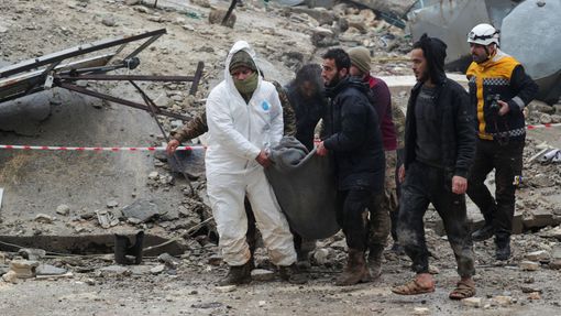 Lidé nesou oběť, zatímco záchranáři hledají přeživší pod troskami po zemětřesení v povstalci ovládaném městě Jandaris v Sýrii.