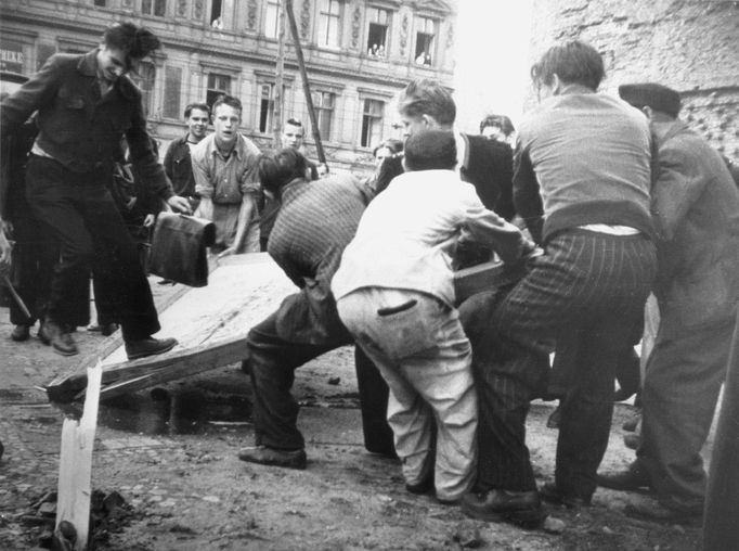 Demonstranti strhávají billboardy.. Záběr z povstání 17. června 1953 ve Východním Berlíně.