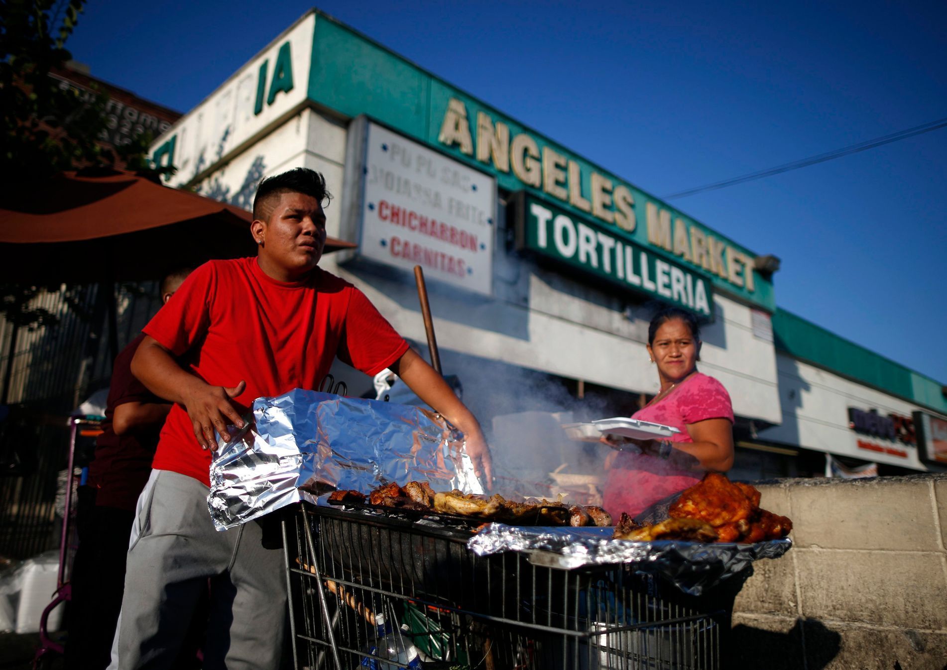 Man cooks meat in a shopping cart in the Westlake area of Los Angeles