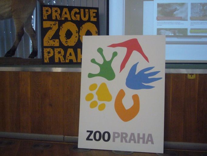 Nové logo nahrazuje to provizorní (v pozadí). Přechod na nový znak bude postupný, aby z toho zoo finančně nevykrvácela.