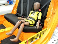 Figurína po crash testu, všimněte si pásu zabořeného do břicha a jiné polohy dítěte.
