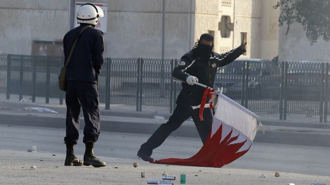 Policista a demonstrant s bahrajnskou vlajkou.