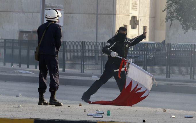 Policista a demonstrant s bahrajnskou vlajkou.